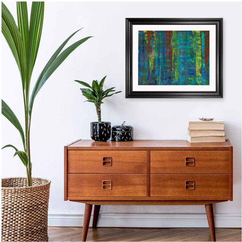 Abstract artwork featuring a mix of vibrant colors, including blue, green, yellow, and red, with vertical textured patterns in a black frame hanging up in a hallway.

