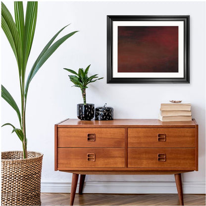 Abstract artwork with dark, blended tones of red, brown, and black, creating a moody gradient effect, placed against white background in a hallway


